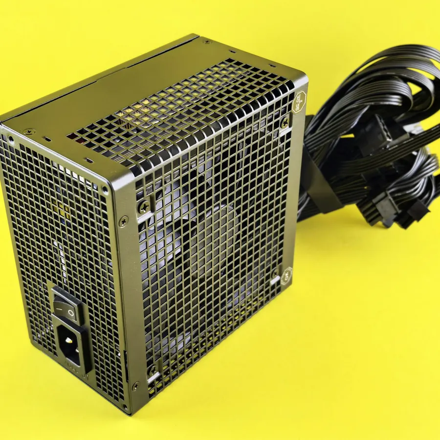 Fuente de poder negra con rejilla y cables modulares sobre fondo amarillo