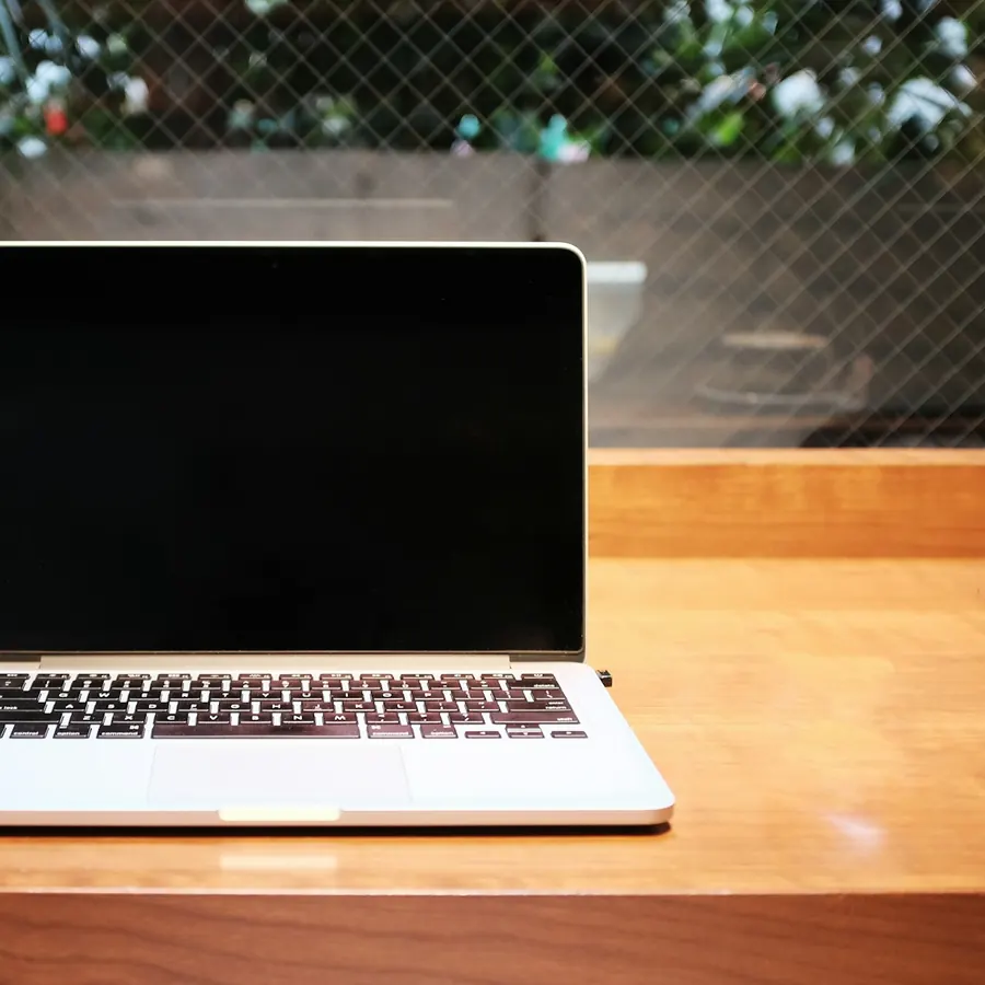 Laptop plateada sobre una barra de madera junto a una taza de café