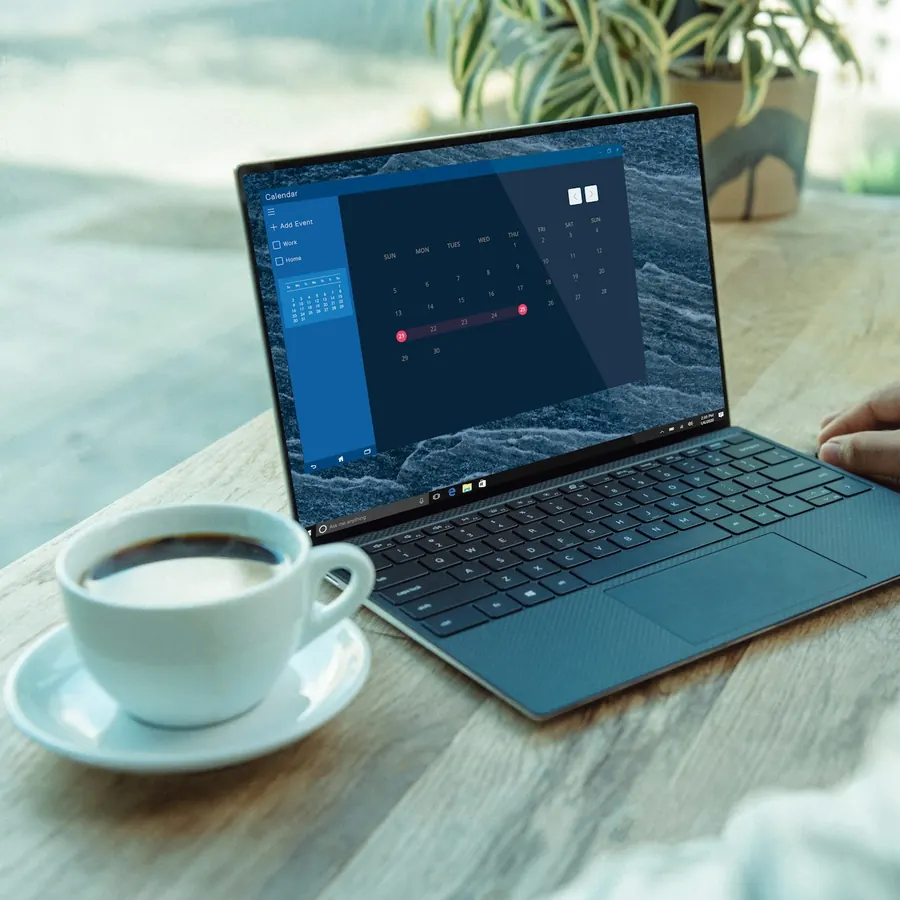 Laptop delgada azul sobre una mesa de madera junto a una taza de café