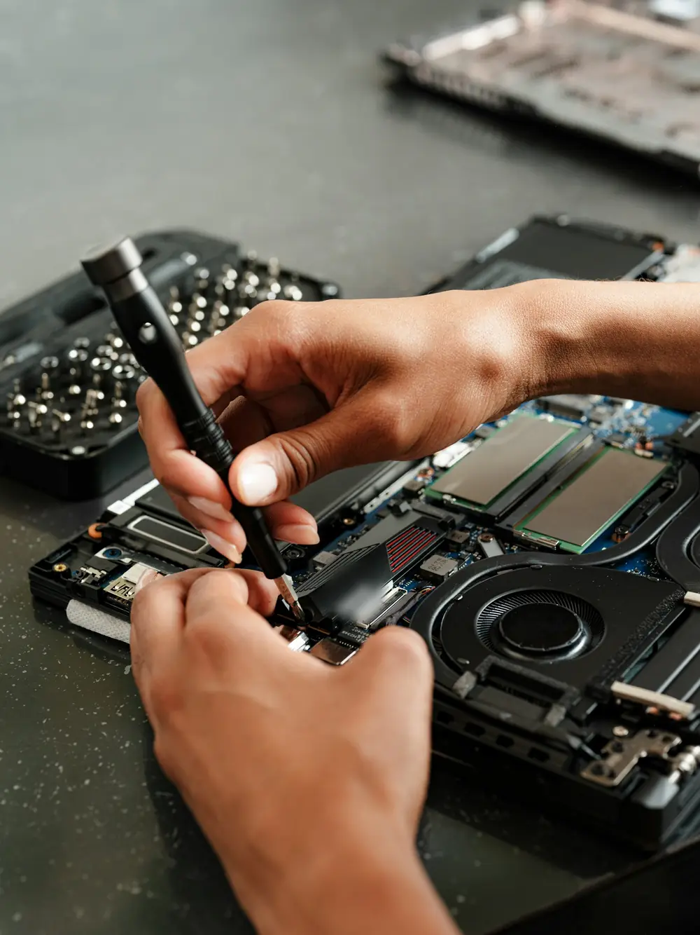 Manos de un técnico reparando una laptop abierta con un destornillador de precisión