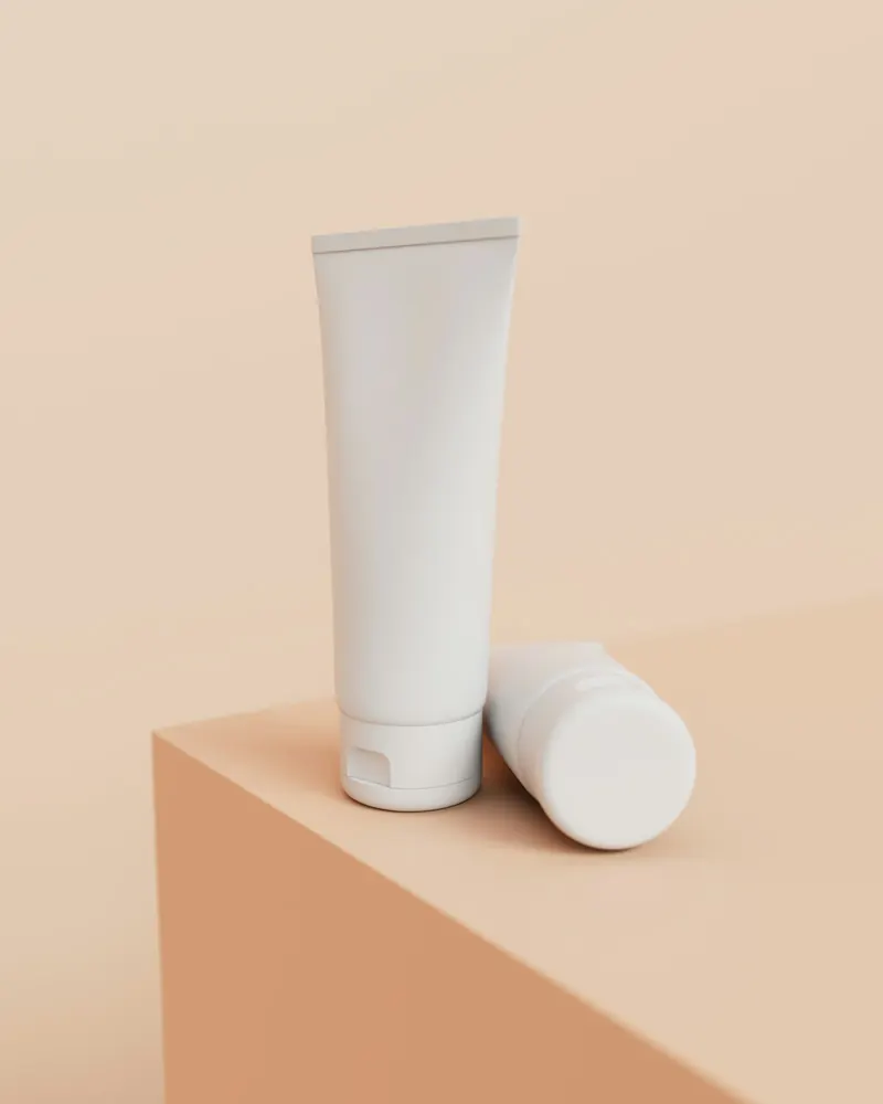 Dos tubos blancos de crema sobre un bloque color durazno
