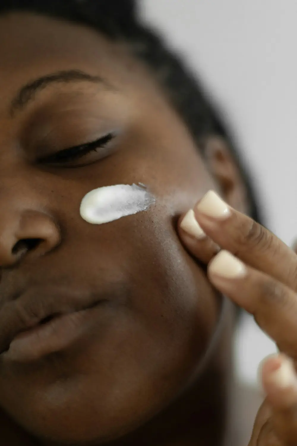 Mujer aplicándose crema en la mejilla