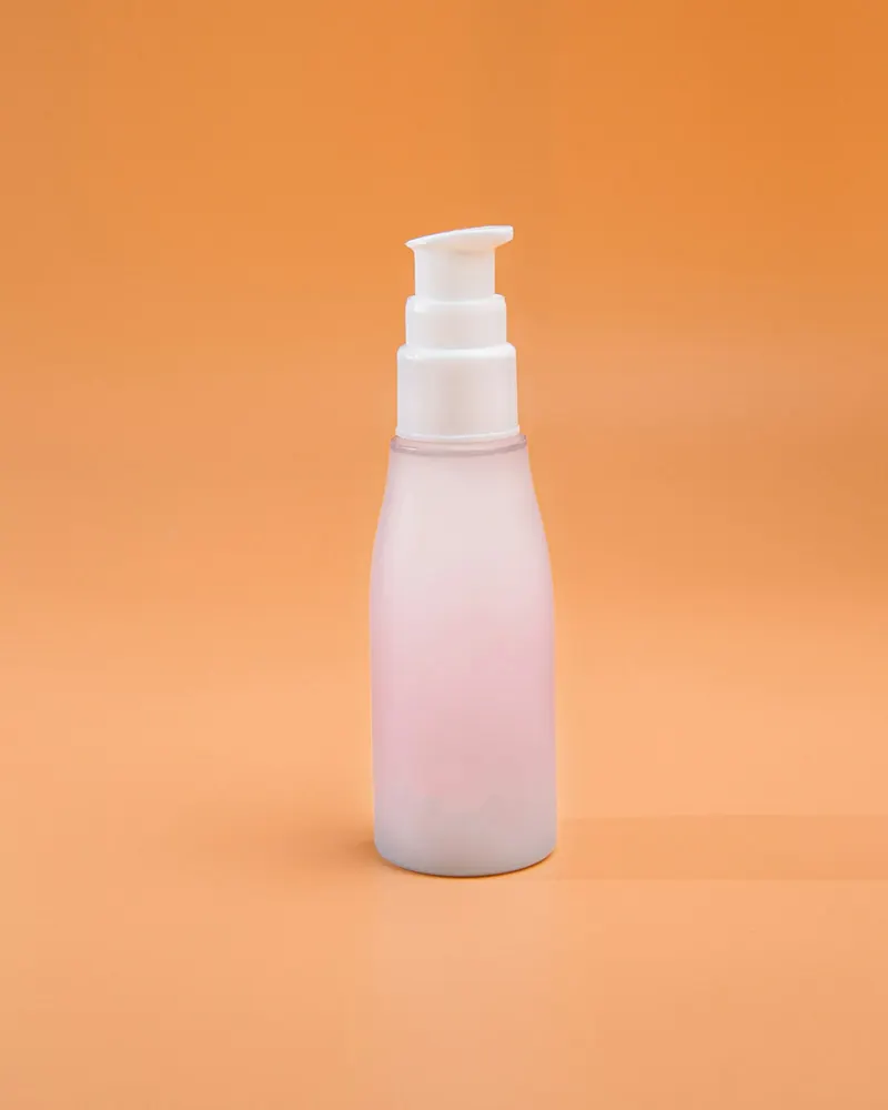 Frasco rosado con dosificador sobre fondo naranja