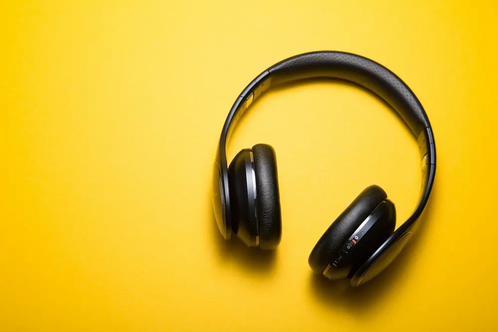 Audífonos inalámbricos negros sobre fondo amarillo